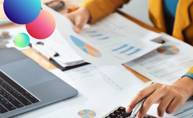 Manos trabajando con papeles con gráficos, una calculadora y un ordenador portátil